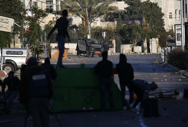 Palestinian youth confront Israeli troops with stones after a house belonging to a Palestinian accused of killing an Israeli soldier a few months ago was blown up in Ramallah in the Israeli-occupied West Bank on December 15, 2018. PHOTO: AFP