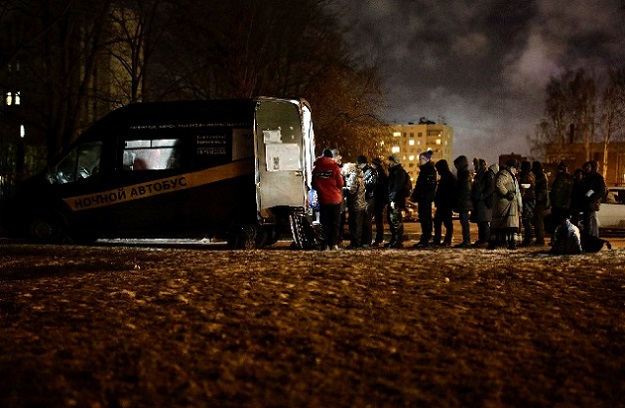 People queue near a van of 'Nochlezhka' charity organization as volunteers distribute meals for the homeless in St. Petersburg, Russia. PHOTO: REUTERS