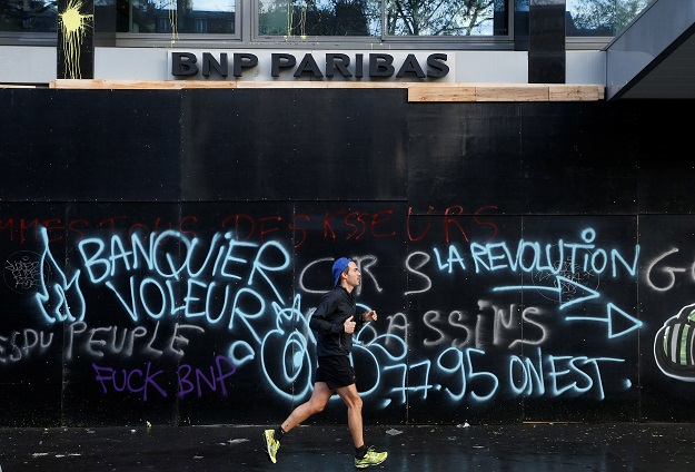 A man jogs past a vandalized bank front the morning after clashes PHOTO: REUTERS