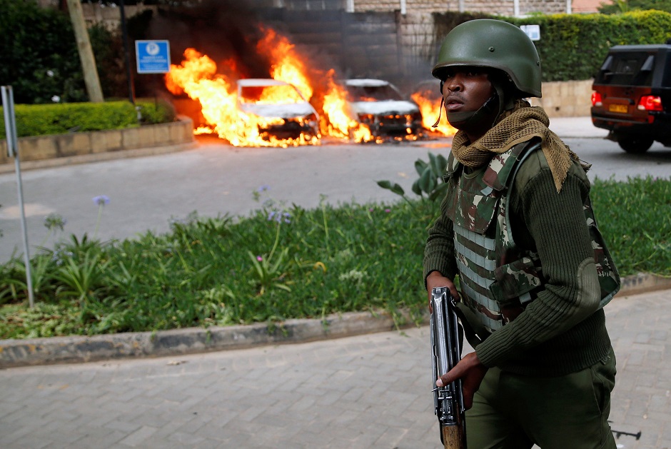 A policeman runs past burning cars at the scene where explosions and gunshots were heard at the Dusit hotel compound, in Nairobi, Kenya. PHOTO: REUTERS 