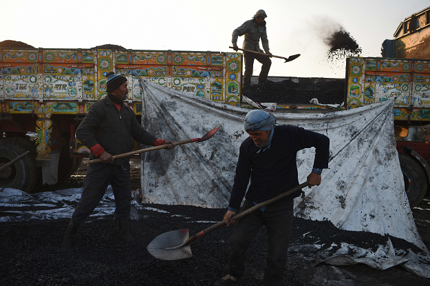 Afghan labourers work at a coal yard amid heavy smog conditions in the outskirts of Kabul. PHOTO: AFP