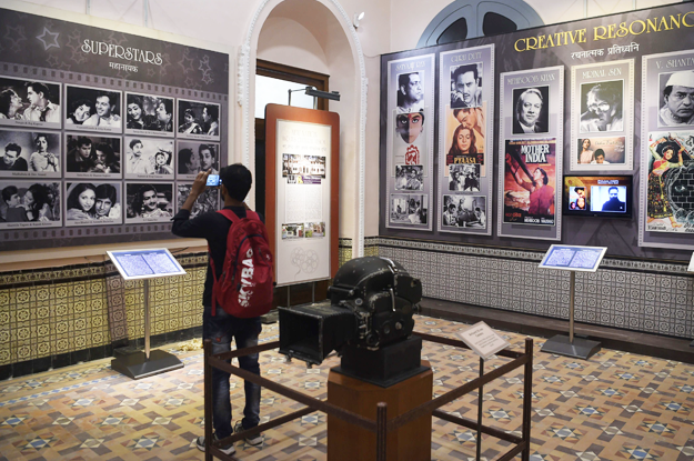 In this picture taken on January 22, 2019, a student takes a picture of a display with images of former Indian movie actors at the National Museum of Indian Cinema (NMIC), the country's first museum showcasing the history of its film industry, in Mumbai. - From silent black-and-white films to colourful blockbusters bursting with song and dance, a new museum tracing the evolution of Indian cinema has opened in the home of Bollywood. Costing 1.4 billion rupees (19.6 million USD), India's first national film museum is spread across a stylish 19th-century bungalow and a modern five-storey glass structure in south Mumbai. (Photo by PUNIT PARANJPE / AFP) 