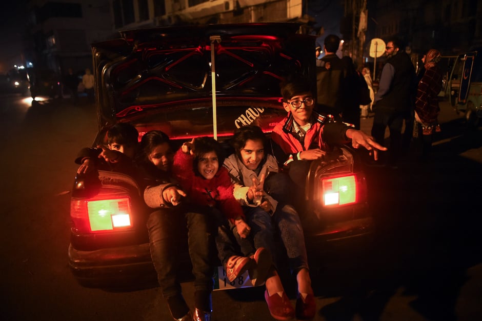 Children enjoy New Year celebrations in a street in Lahore from the back of a car. PHOTO: AFP