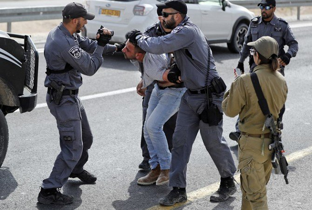 a file photo of an israeli policeman filming a palestinian as others hold him as he is being detained on october 19 2018 photo afp