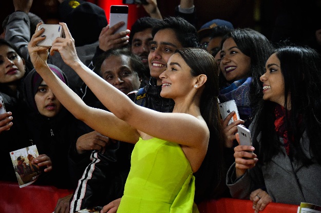 British actress Alia Bhatt poses for selfies with fans as she for on the red carpet before the premiere of the film 