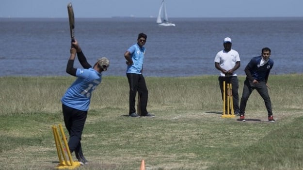 Indians living in Uruguay play a shot during a cricket match along Montevideo's seaside promenade. PHOTO: AFP