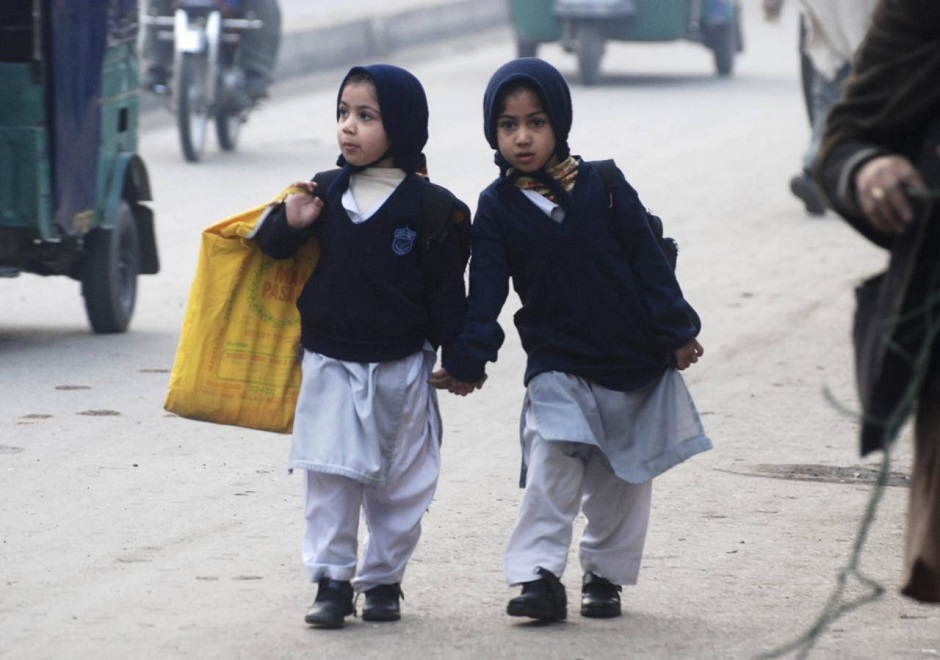 Girls carry their school bags as they walk along a road while heading to their school in Peshawar. PHOTO: REUTERS