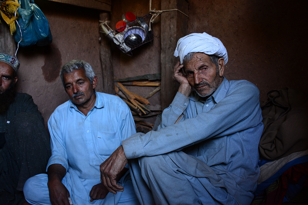 Kashmiri resident Chaudhry Hakam Deen (2nd R) sits with relatives in their bunker next to their house in Dhanna village. PHOTO: AFP