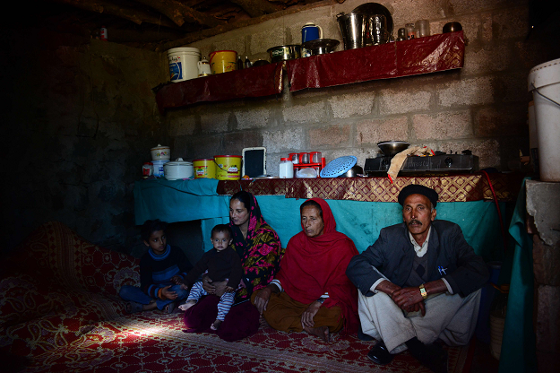 Kashmiri Ulfat Bibi (2nd R) and her daughter-in-law Jameela Akhtar (L) sit in their bunker with family inside their house in Dhanna village. PHOTO: AFP