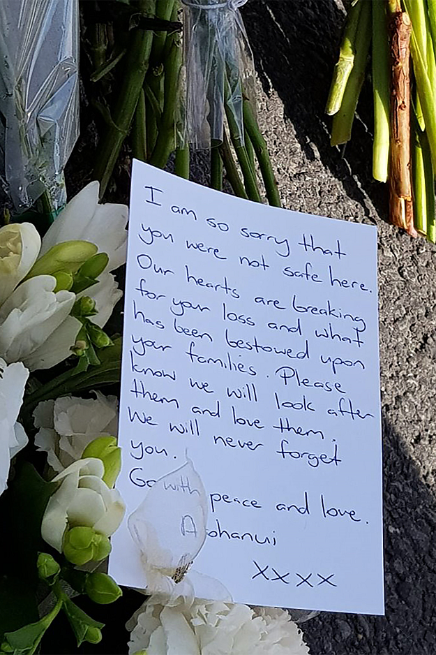 A letter is seen as residents pay their respects by placing flowers for the victims of the mosques attacks in Christchurch . PHOTO:AFP