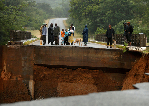 Locals look at a washed away bridge. PHOTO: REUTERS