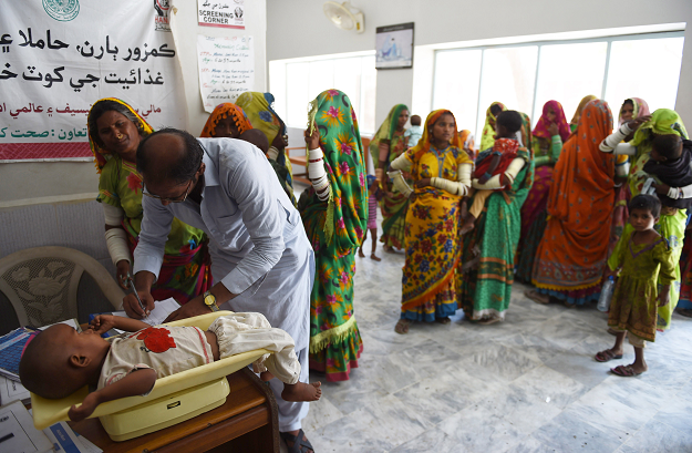 A paramedic weighs a child at Mithi Civil Hospital. PHOTO: AFP