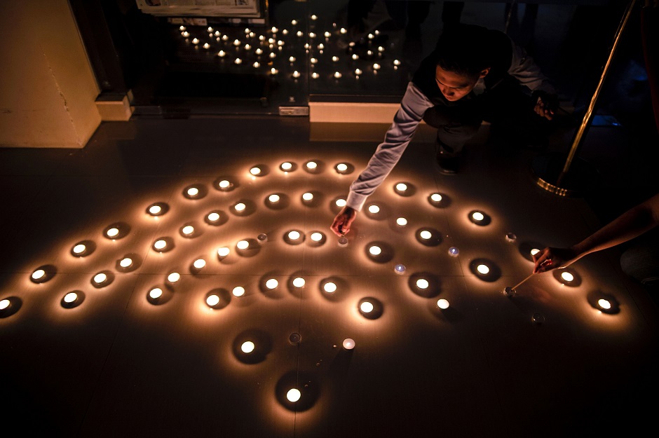 An Indonesian man lights up candles to create the shape of the wifi signal for the Earth Hour environmental campaign in Surabaya, East Java province, on March 30, 2019. - The 13th edition of Earth Hour, organised by the green group WWF, will see millions of people across 180 countries turn off their lights at 8:30 pm local time to highlight energy use and the need for conservation. PHOTO: AFP