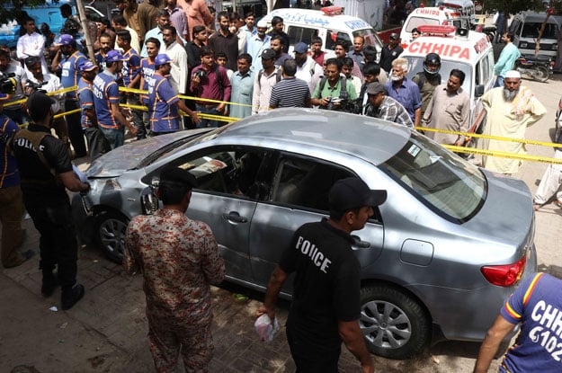  Security personnel and onlookers gather around the car of leading religious scholar Mufti Taqi Usmani after an attack by unidentified gunmen in Karachi. PHOTO: AFP 