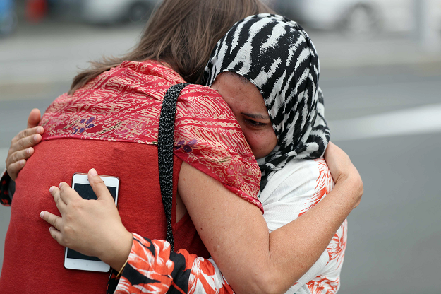 Residents hug each other after paying their respects by placing flowers for the victims of the mosques attacks in Christchurch at the Masjid Umar mosque in Auckland on March 17, 2019. PHOTO: AFP