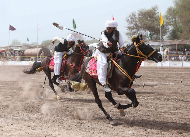 This photograph taken on March 27, 2019, shows Pakistani horse riders with lances used to pick up pegs during an attempt for a Guinness World Record for tent pegging in Khanewal district in Punjab province. PHOTO: AFP