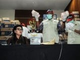 This picture taken on March 28, 2019 shows Basariah Panjaitan (L), deputy chairperson of the corruption eradication commission (KPK), seated alongside KPK officers along with boxes of Indonesian currency totalling over 560,000 USD, seized from a lawmaker's office, during a press conference in Jakarta ahead of the country's general elections. PHOTO: AFP