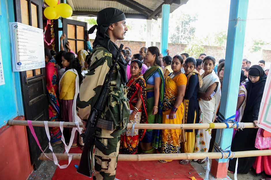 An Indian security personnel stands guard as voters queue to cast their vote at a polling station during India's general election in Samuguri village, some 140 km from Guwahati, the capital city of India's northeastern state of Assam on April 11, 2019. PHOTO: AFP