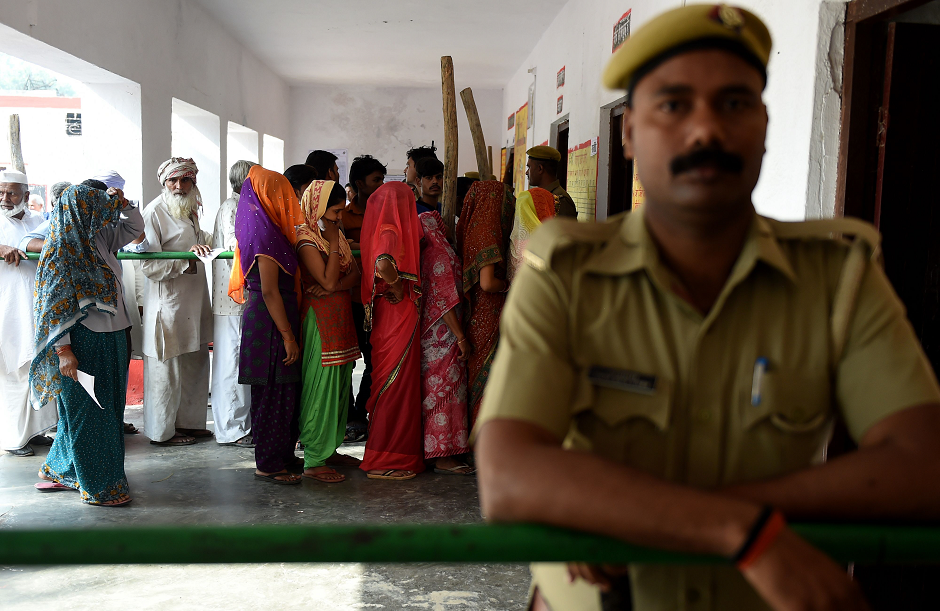 An Indian policeman stands guard as Indian voters queue to caste their vote at a polling station during India's general electionin in Kawaal village near Muzaffarrnagar in the northern Indian state of Uttar Pradesh on April 11, 2019. PHOTO: AFP