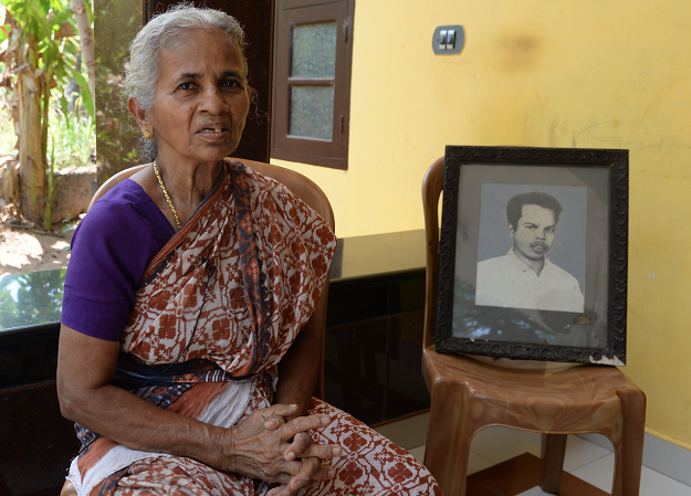 In this photo taken on April 20, 2019, B.N. Leela, the widow of Vadekkal Ramakrishnan, who was one ot the first Rashtriya Swayamsevak Sangh (RSS) members killed in political violence, sits beside the portrait of her late husband during an interview with AFP at Thalaserry in the southern Indian state of Kerala. PHOTO: AFP
