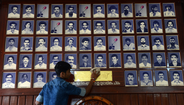 In this photo taken on April 20, 2019, a worker dusts memorial portraits of party workers killed in political violence hanging at the Rashtriya Swayamsevak Sangh (RSS) office at Thalaserry in the southern Indian state of Kerala. PHOTO: AFP