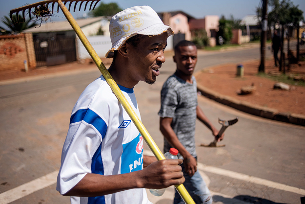 Chesney Van Wyk (L) and Lorenco Jacob (R), members of the coloured community of Eldorado Park, walk back to their dwellings after a land grabbing action on the outskirts of Johannesburg, on April 18, 2019. PHOTO: AFP