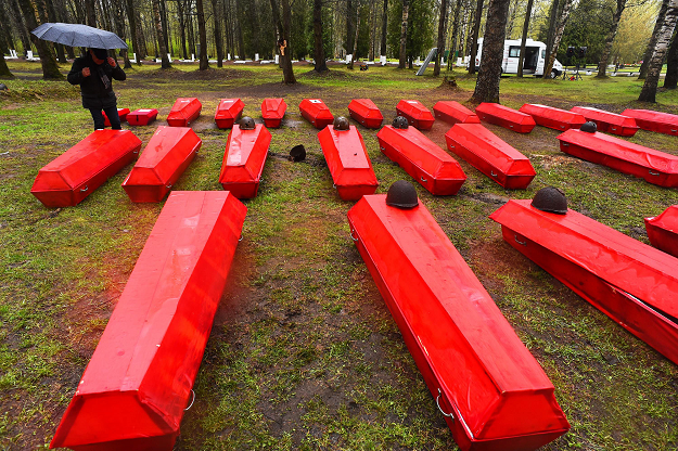 A man stands by coffins with the remains of Red Army soldiers killed in World War Two. PHOTO: AFP