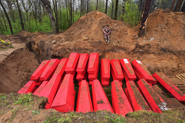 A boy sits next to a mass grave with coffins with the remains of Red Army soldiers killed in World War Two. PHOTO: AFP