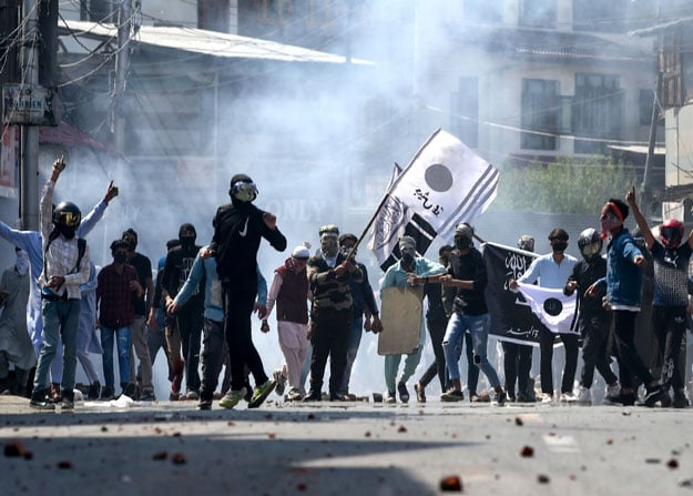 Protesters gesture towards Indian police personnel through teargas smoke during a clash in occupied Kashmirâs Srinagar on May 31, 2019. PHOTO: AFP
