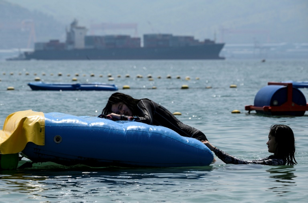 People swim at a beach in Subic Bay where a container ship hired by Canada is loaded with trash that the Philippines has ordered returned. PHOTO: AFP