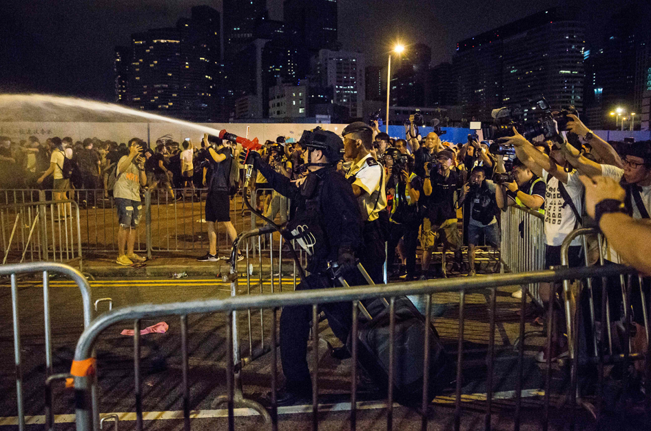 A police officer (C) uses pepper spray during clashes with protesters after a rally against a controversial extradition law proposal in Hong Kong on June 10, 2019. - Hong Kong witnessed its largest street protest in at least 15 years on June 9 as crowds massed against plans to allow extraditions to China, a proposal that has sparked a major backlash against the city's pro-Beijing leadership. Photo: AFP