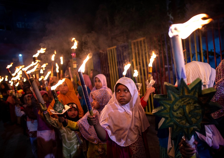 TOPSHOT - This picture taken on late June 4, 2019 shows young Indonesian Muslims taking part in a parade to celebrate Eid al-Fitr festival in Surabaya. - Muslims around the world celebrate the Eid al-Fitr holiday, which marks the end of the fasting month of Ramadan. (Photo by Juni Kriswanto / AFP)