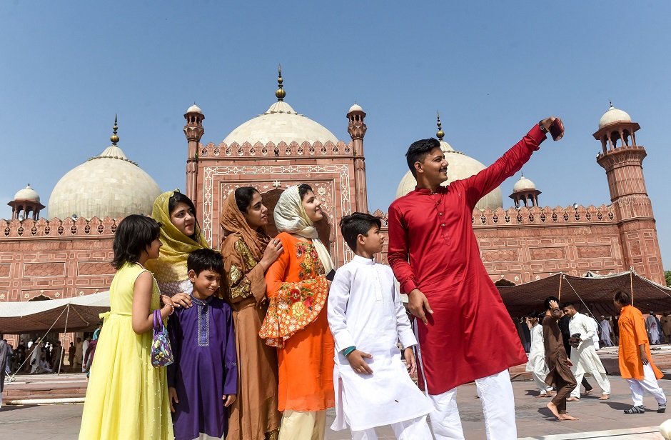 A Pakistani Muslim takes a selfie with his family after offering prayers during Eid al-Fitr at the Badshahi Mosque in Lahore on June 5, 2019. - Muslims around the world are celebrating the Eid al-Fitr festival, which marks the end of the fasting month of Ramadan. (Photo by ARIF ALI / AFP)