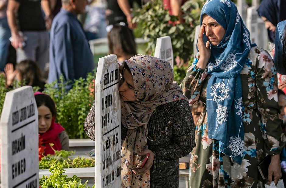 TOPSHOT - Relatives of Kurdish-dominated Syrian Democratic Forces' fighters who have been killed during the Syrian conflict, pray at the tomb of loved ones on the first day of Eid al-Fitr holiday, that marks the end of the Muslim fasting month of Ramadan, in the northeastern Syrian city of Qamishli on June 5, 2019. (Photo by Delil souleiman / AFP)