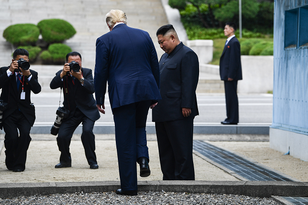 US President Donald Trump steps into the northern side of the Military Demarcation Line that divides North and South Korea, as North Korea's leader Kim Jong Un looks on, in the Joint Security Area (JSA) of Panmunjom in the Demilitarized zone (DMZ) on June 30, 2019. PHOTO: AFP
