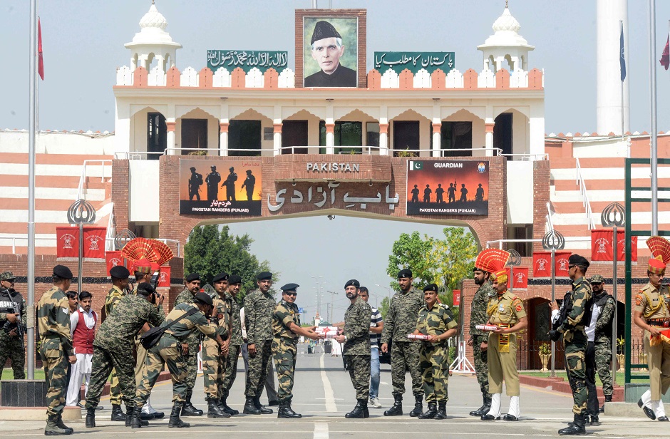 Pakistani Wing Commander Usman Ali (C-R) offers sweets to the Indian Border Security Force (BSF) commandant Mukund Kumar Jha (C-L) on the occasion of Eid al-Fitr at the India Pakistan Wagah Border post about 35 km from Amritsar on June 5, 2019. - Muslims around the world are celebrating the Eid al-Fitr festival, which marks the end of the fasting month of Ramadan. (Photo by NARINDER NANU / AFP)
