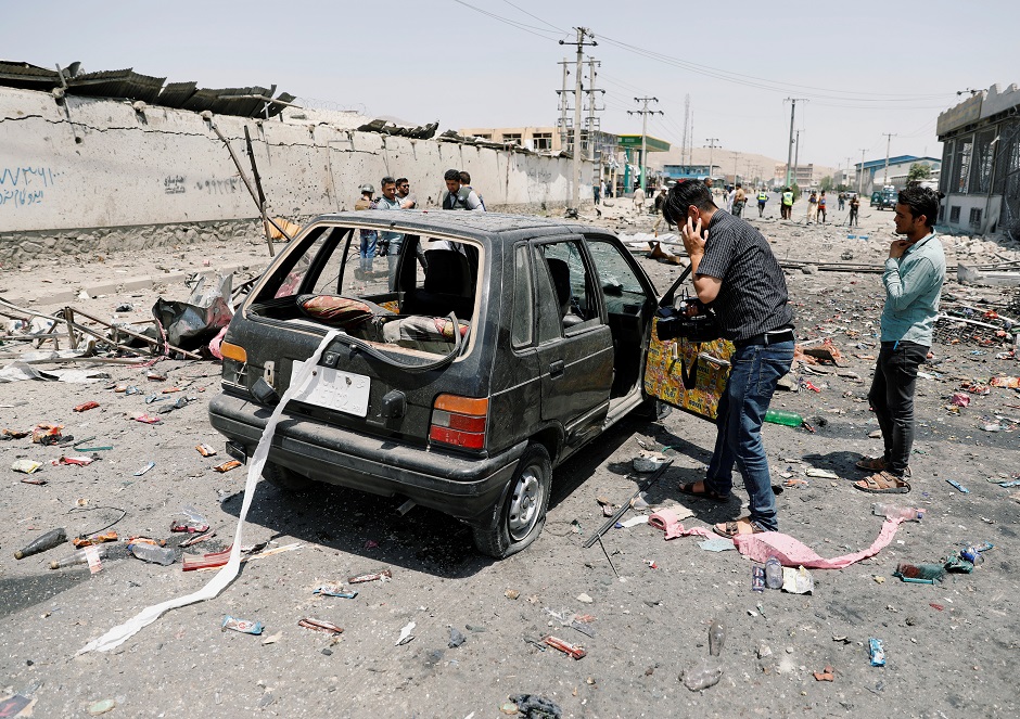 A cameraman films a damaged car at the site of a blast in Kabul, Afghanistan. PHOTO: Reuters
