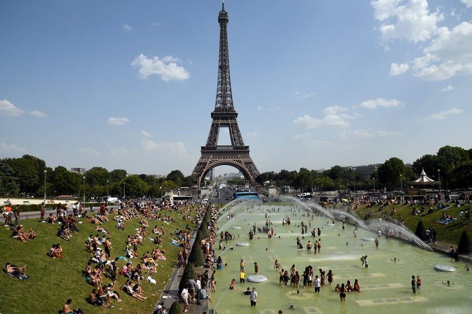 People cool off and sunbathe by the Trocadero Fountains next to the Eiffel Tower in Paris.  PHOTO: AFP