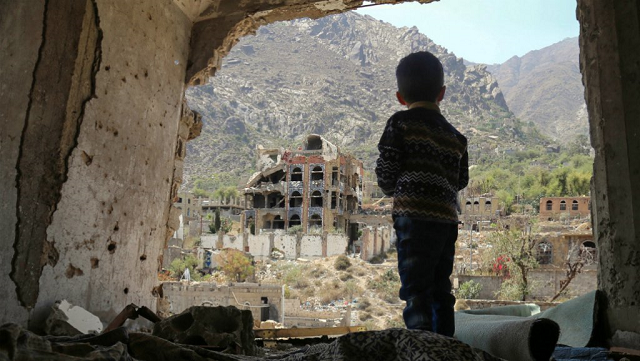 A photo taken on March 18, 2018, shows a Yemeni child looking out at buildings that were damaged in an air strike in the southern Yemeni city of Taez. (PHOTO: AFP)