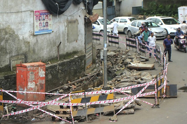 indian commuters walk past the spot where a toddler fell inside a sewage drain in mumbai photo afp