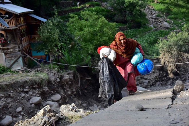 picture flood affected victims walk past a damaged road in laswa valley ajk photo afp