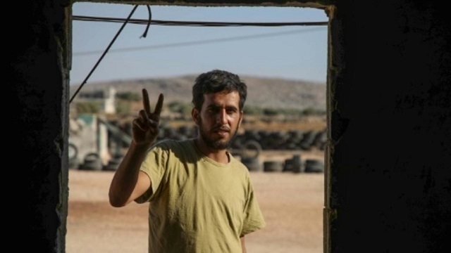mohammad al naeemi a syrian who returned from exile in germany to join a rebel group flashes a victory sign at a training camp near the bab al hawa crossing between iblib province and turkey on july 18 2019 photo afp