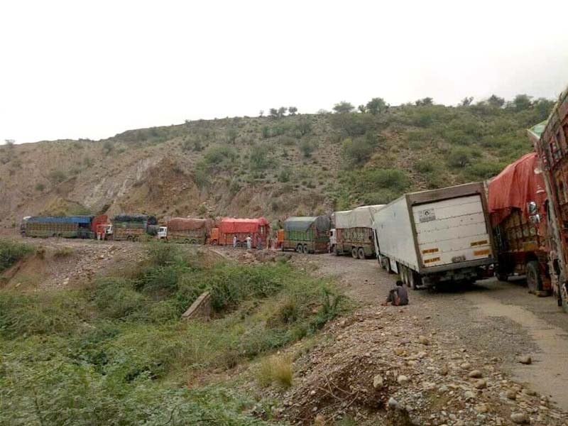 trucks and other vehicles wait as a landslide is cleared in di khan photo express