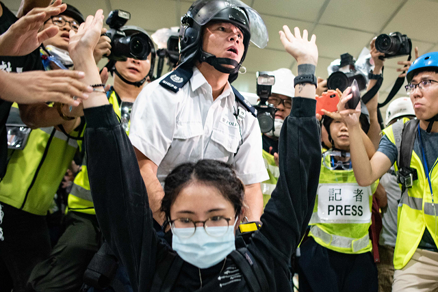a protester gestures as a policeman looks on inside a shopping arcade in sha tin of hong kong after a rally against a controversial extradition law proposal in sha tin district of hong kong on july 14 2019 photo afp