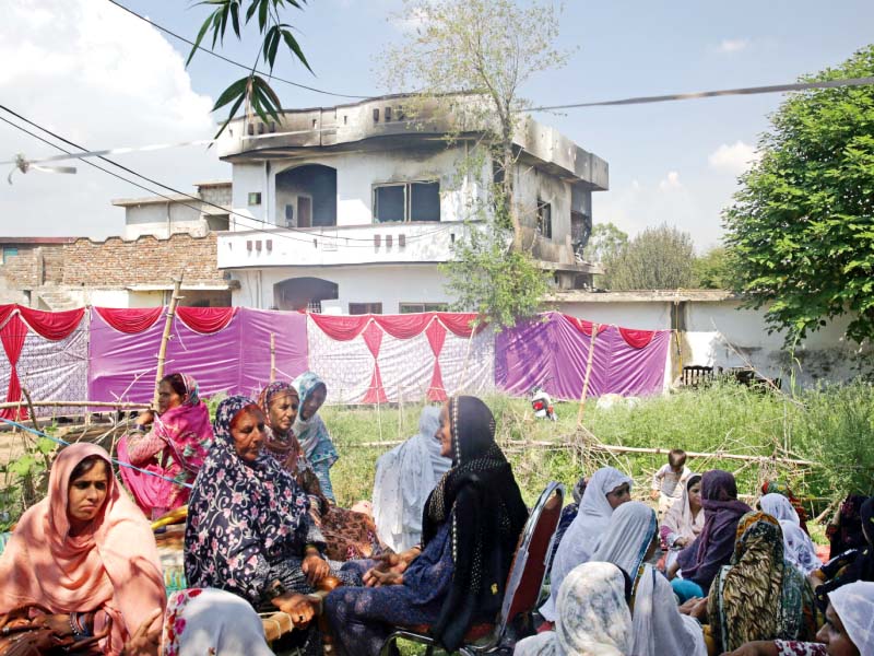 a man injured the airplane crash walks out of a hospital top left family members comfort sabar jaan as she mourns for her family members top right women and children sit near a damaged building with smoke stains photos reuters afp