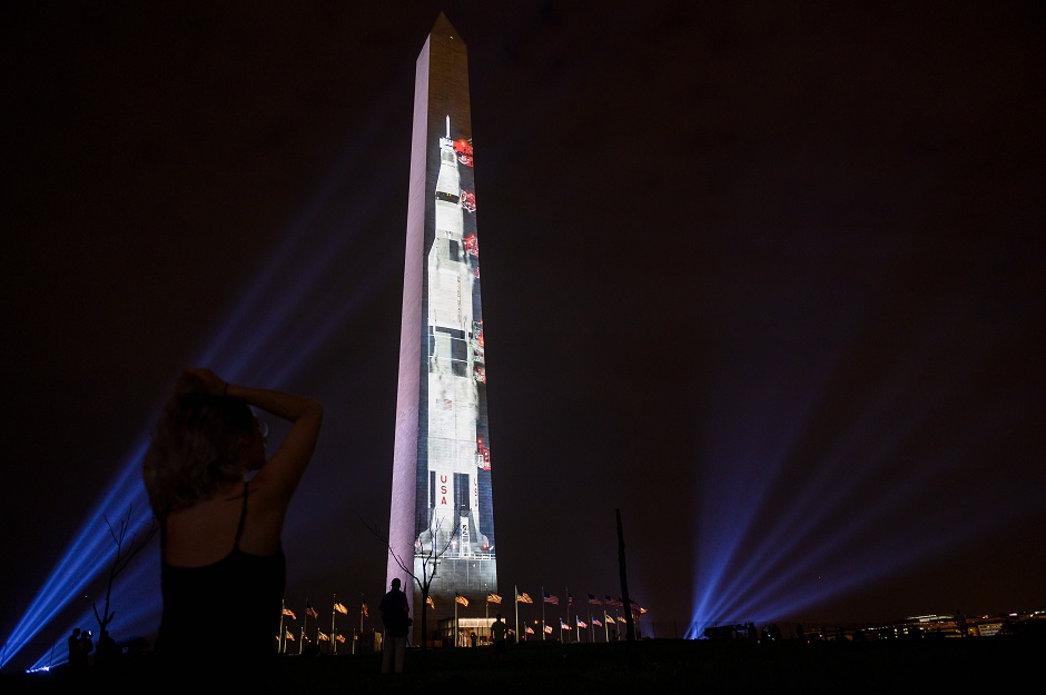  People look at an image of a Saturn V, the rocket that sent Apollo 11 into orbit on July 16, 1969, is projected on the Washington monument in Washington: AFP
