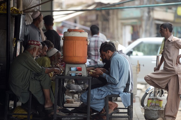 In this picture, people eat charity food at a roadside restaurant in Rawalpindi. PHOTO: AFP 