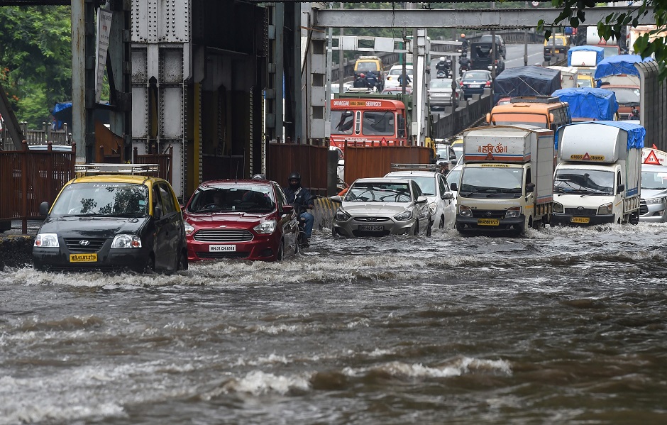 Commuters drive on a flooded road after heavy rain showers in Mumbai. PHOTO: AFP