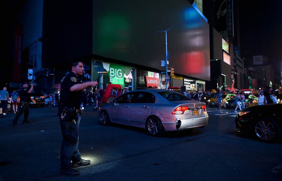 A police officer directs transit with Times Square's billboards in the background after a power outage hit Manhattan in New York City. PHOTO: Reuters