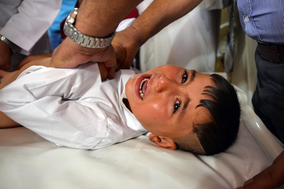 A young Muslim boy reacts as he's being circumcised by a doctor in the Iraqi holy central city of Najaf. PHOTO: AFP